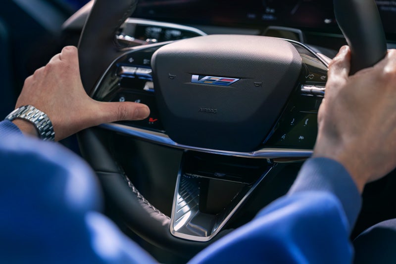 Close-up of a Man About to Press the V-Button on the 2026 OPTIQ-V Steering Wheel | Bomnin Cadillac Nanuet in Nanuet NY
