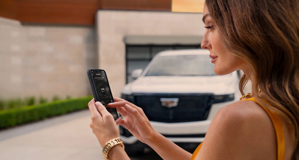 lady checking her mobile with a Cadillac vehicle background | Bomnin Cadillac Nanuet in Nanuet NY